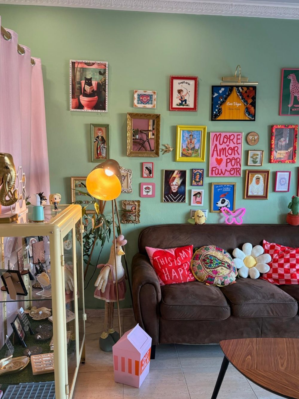 Sala de espera con un sofá, cojines de colores y una pared llena de cuadros