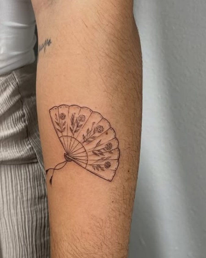 Tatuaje de línea fina de un abanico con flores en el antebrazo