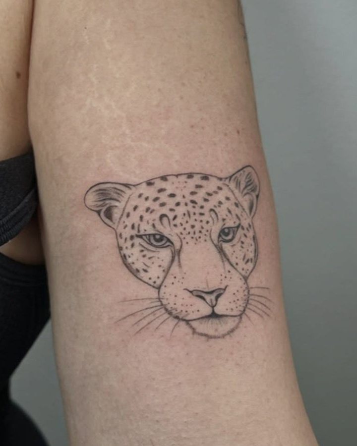 Tatuaje de la cara de un leopardo en el brazo, en línea fina y sombreado suave