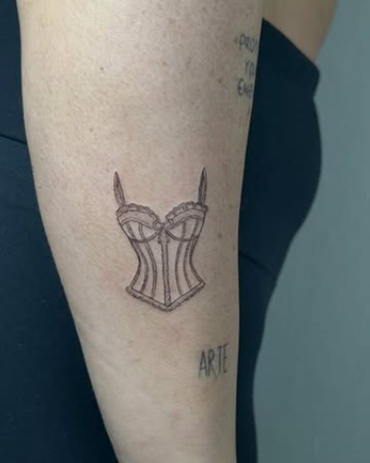 Tatuaje de un corsé en el antebrazo, en línea fina
