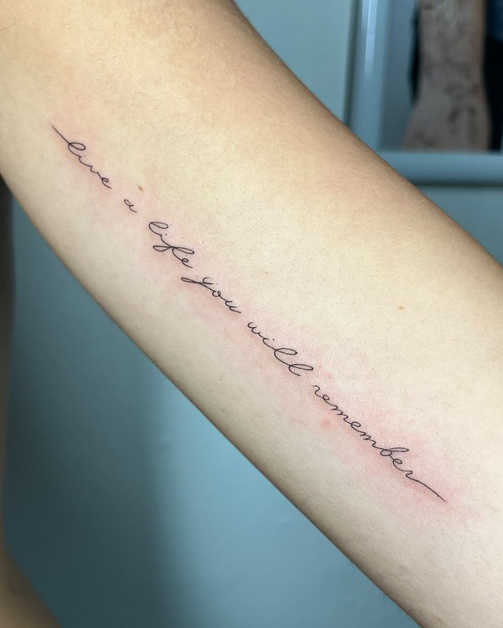 Frase «love a life you will remember» en letra manuscrita a lo largo del brazo