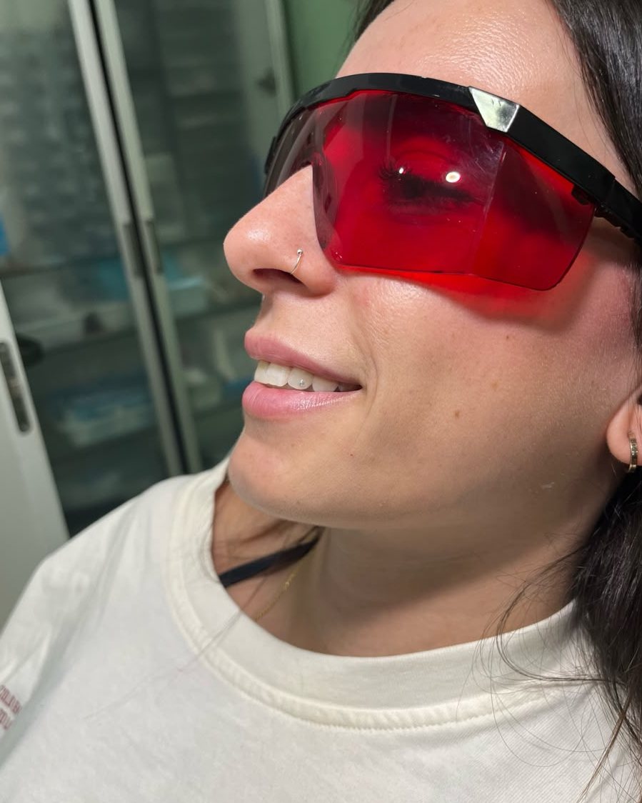 Clienta con gafas de protección rojas tras ponerse una gema dental